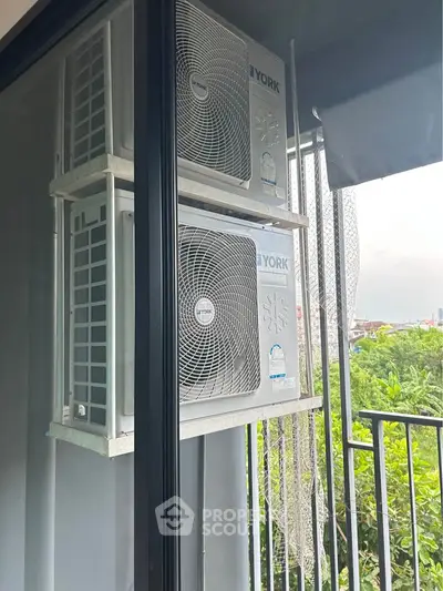 Modern balcony with air conditioning units overlooking lush greenery, perfect for urban living.