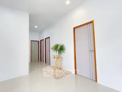 Minimalist hallway with white walls and multiple doors, featuring a small decorative table.