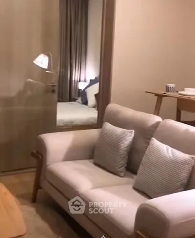 Cozy living room with modern sofa and view into a stylish bedroom