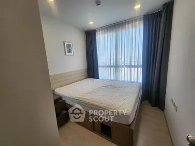 Cozy bedroom with large window and modern furnishings in a bright apartment.