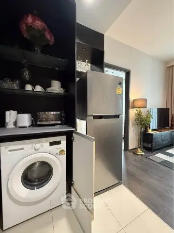 Modern apartment interior with washing machine and fridge in open kitchen layout.