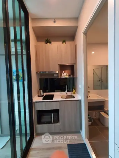 Modern compact kitchen with sleek cabinetry and adjacent bathroom view