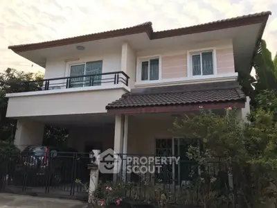 Charming two-story house with balcony and lush garden in serene neighborhood.
