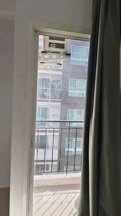 Modern apartment balcony with sliding door and city view, perfect for urban living.