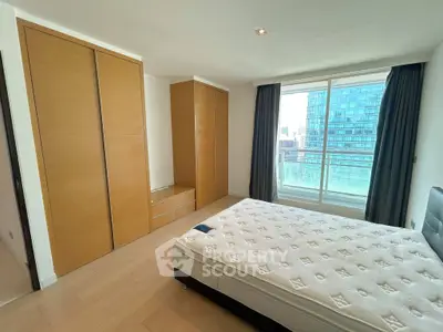 Spacious bedroom with large window offering city view, featuring built-in wardrobes and a comfortable bed.