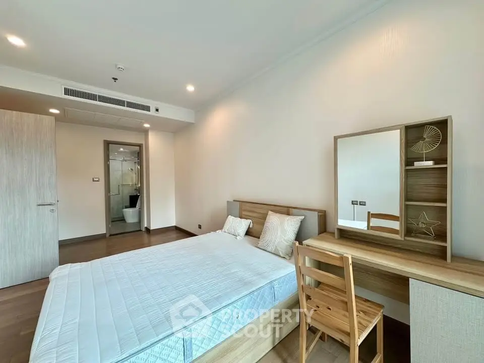 Spacious bedroom with modern furnishings and ensuite bathroom in a stylish apartment.