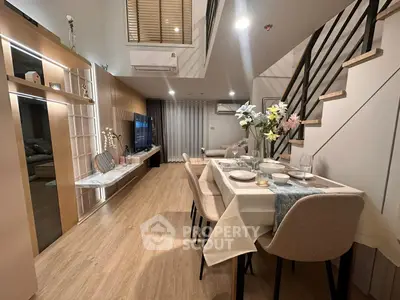 Modern open-plan living and dining area with stylish decor and elegant staircase.