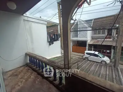 Charming balcony view in a residential neighborhood with parked car and laundry area.