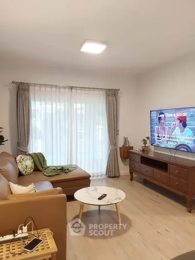 Cozy living room with modern decor, featuring a comfortable sofa, stylish coffee table, and large TV for entertainment.