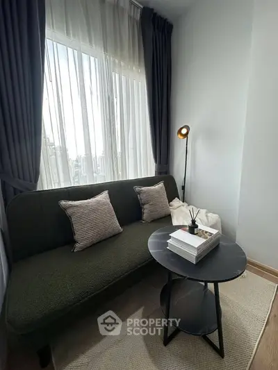Cozy living room with stylish sofa, floor lamp, and round coffee table by a large window.