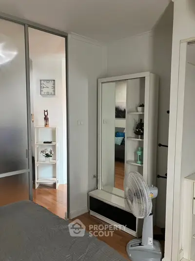 Cozy bedroom with modern decor and sliding door, featuring a stylish mirror and wooden flooring.