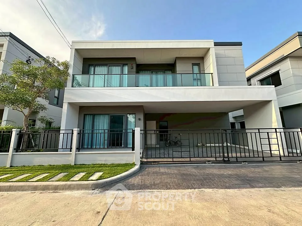 Modern two-story house with sleek design and spacious balcony in a suburban neighborhood.