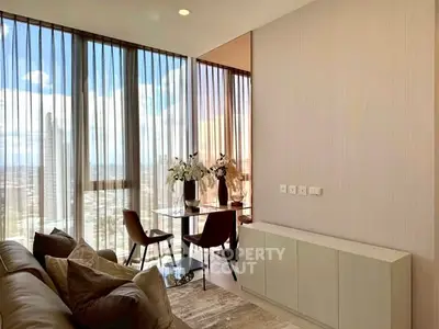 Modern living room with floor-to-ceiling windows and city view, featuring elegant furniture and decor.