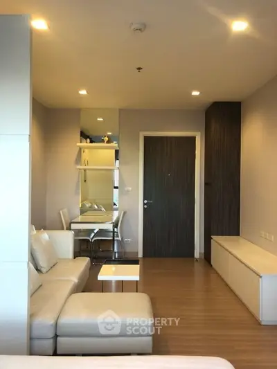 Modern living room with sleek furniture and dining area in open layout apartment.