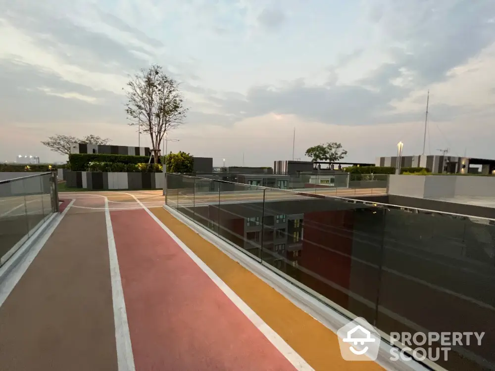 Modern rooftop with glass railings and colorful pathways at sunset