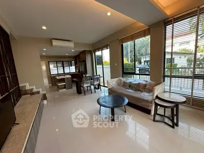 Spacious modern living room with open layout and large windows offering natural light and garden view.