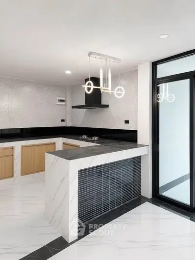 Modern kitchen with sleek marble countertops and stylish lighting in a contemporary home.