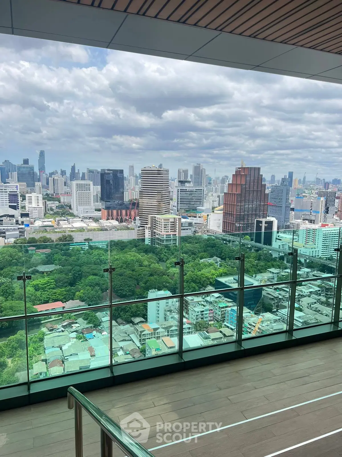 Stunning cityscape view from a modern high-rise balcony with glass railing.