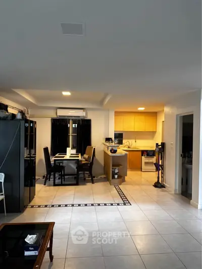 Spacious open-plan living and dining area with modern kitchen and elegant tile flooring.