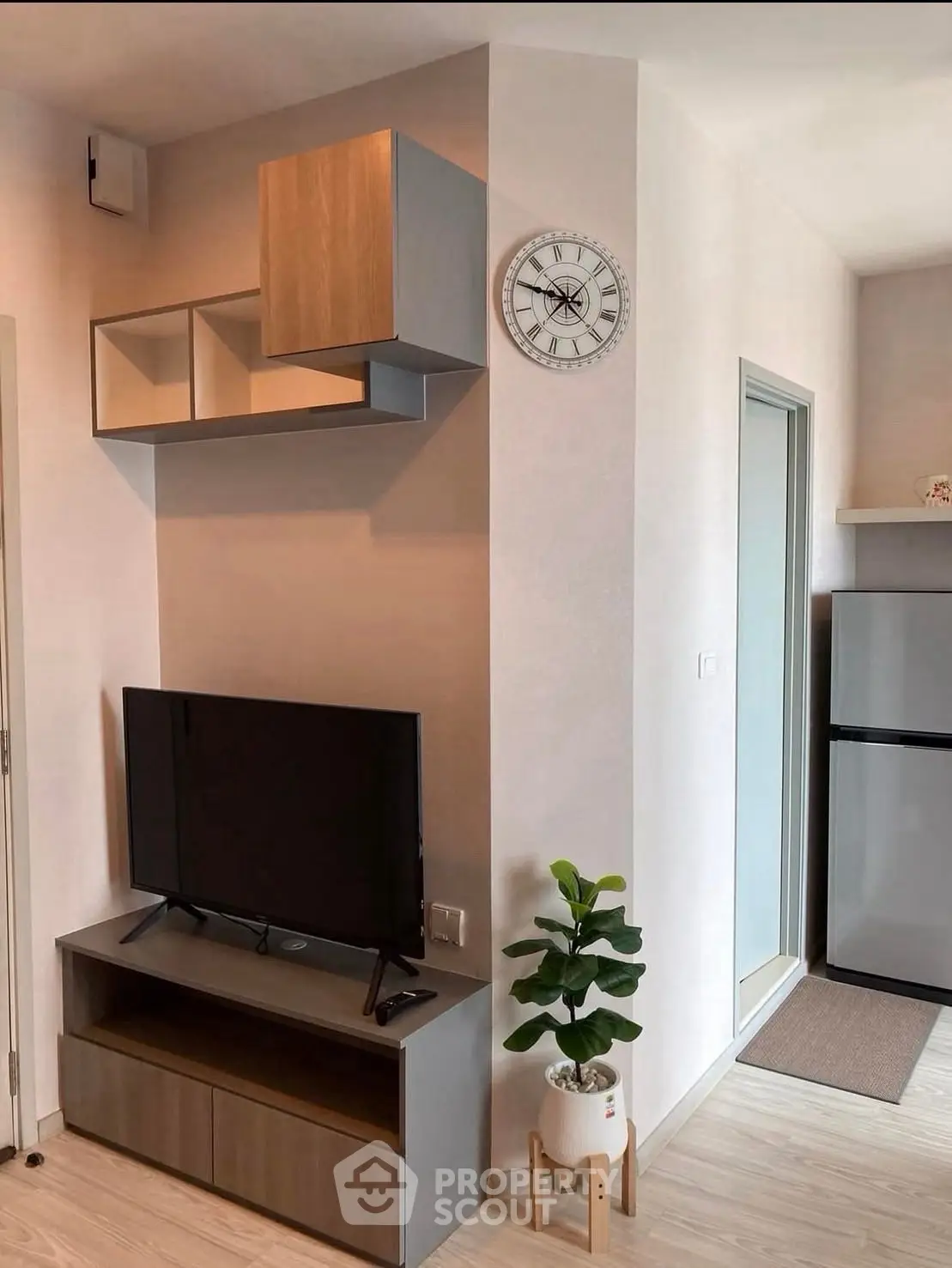 Modern living room with sleek TV stand, wall clock, and potted plant, showcasing minimalist interior design.