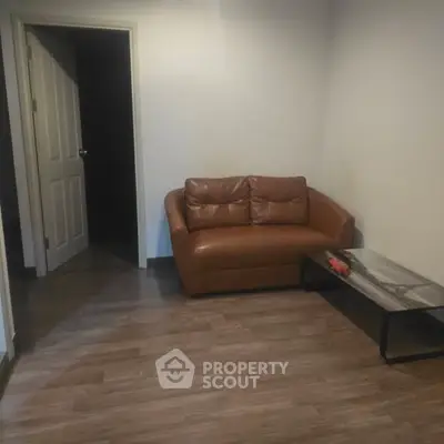 Cozy living room with brown leather sofa and modern coffee table on wooden flooring.