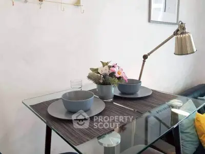 Modern dining setup with glass table and stylish decor in cozy living space.