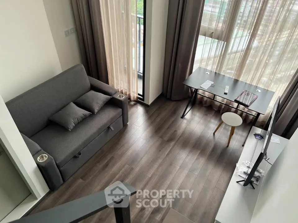 Modern living room with sleek furniture and large windows offering natural light and city views.
