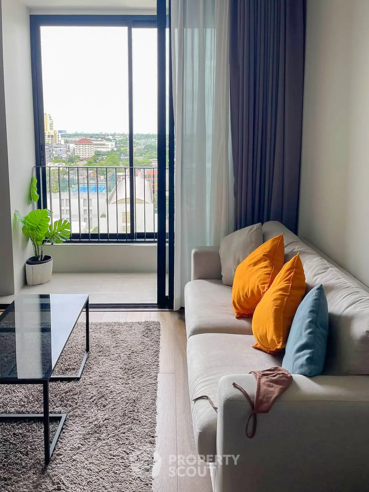 Chic living room with cozy sofa, vibrant pillows, and balcony view in modern apartment.