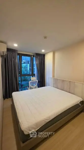 Cozy bedroom with large window and modern furnishings in a stylish apartment.
