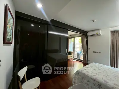 Spacious bedroom with modern decor and large windows offering natural light and garden view.