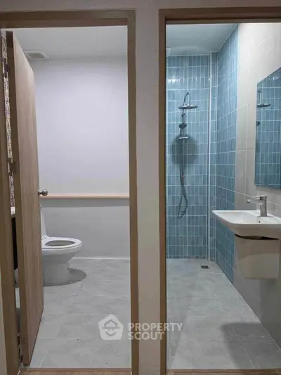 Modern bathroom with separate shower and toilet areas, featuring sleek blue tiles and contemporary fixtures.