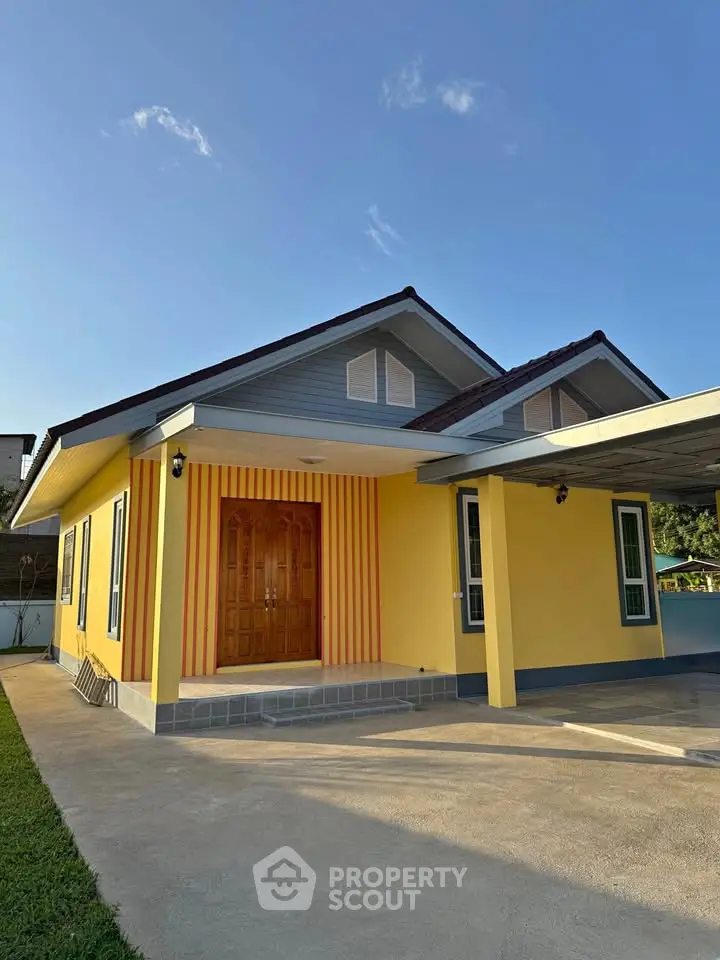 Charming yellow house with inviting entrance and spacious driveway under clear blue sky.