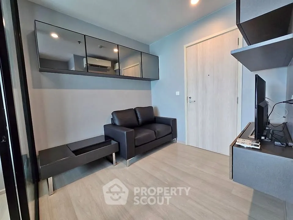 Modern living room with sleek black sofa and wall-mounted TV in stylish apartment.