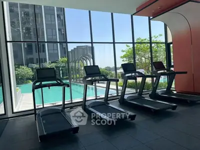 Modern gym with treadmills overlooking a scenic pool and lush greenery, offering a luxurious fitness experience.