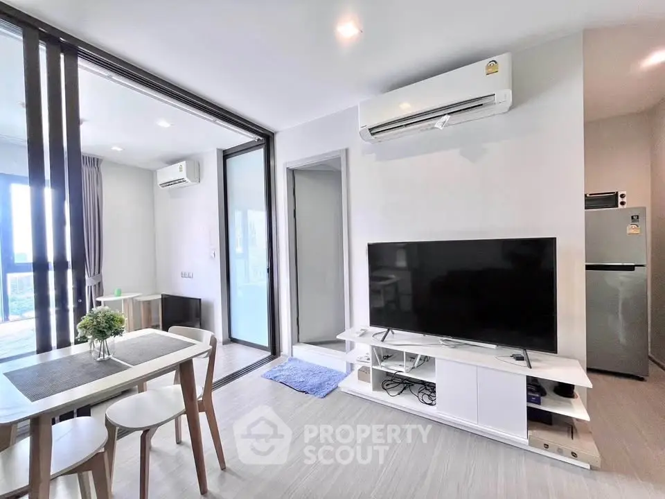 Modern living room with sleek furniture and air conditioning, featuring a TV and dining area.