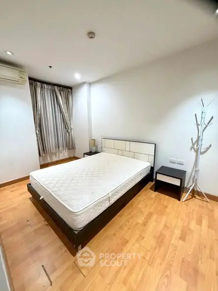 Spacious bedroom with wooden flooring and modern furnishings in a stylish apartment.