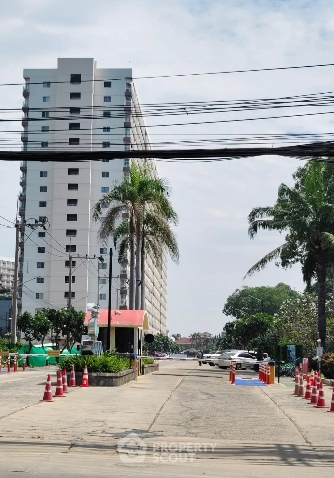 Modern high-rise building with palm trees and secure entrance in urban setting.