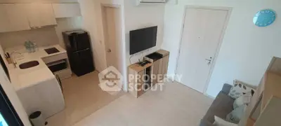 Modern compact living room with open kitchen, featuring sleek appliances and minimalist design.