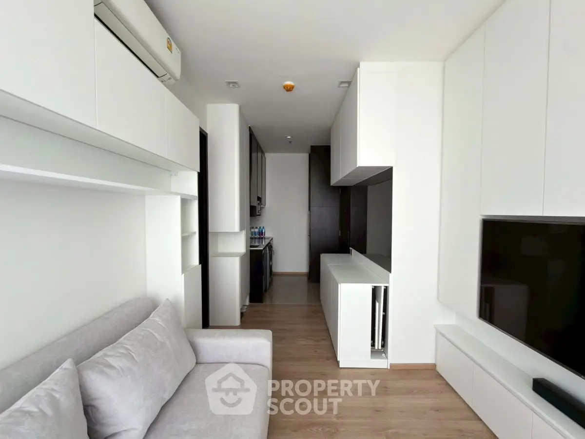 Modern living room with sleek white cabinetry and cozy gray sofa