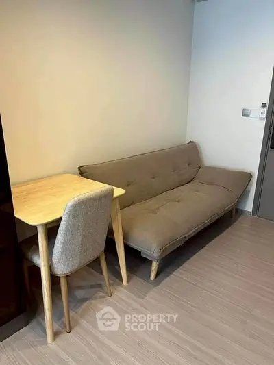 Cozy living room with modern sofa and wooden table, perfect for compact spaces.