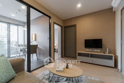 Modern living room with open view to dining area and balcony, featuring sleek furniture and neutral tones.