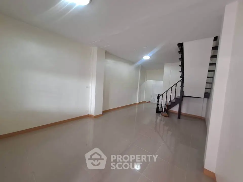 Spacious empty room with staircase and glossy tiled floor, ideal for customization.