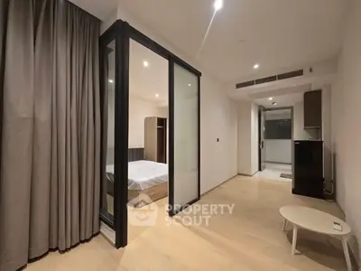 Modern apartment interior with bedroom and living area, featuring sleek design and wooden flooring.