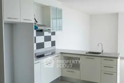 Modern kitchen with sleek white cabinets and granite countertops in a bright apartment.