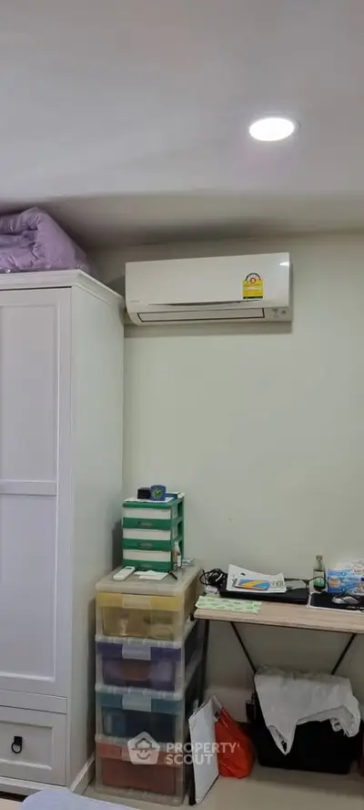 Cozy bedroom corner with air conditioning and organized storage solutions.