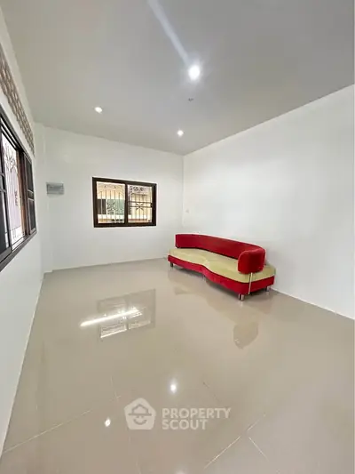 Spacious living room with modern red sofa and large windows, perfect for natural light.