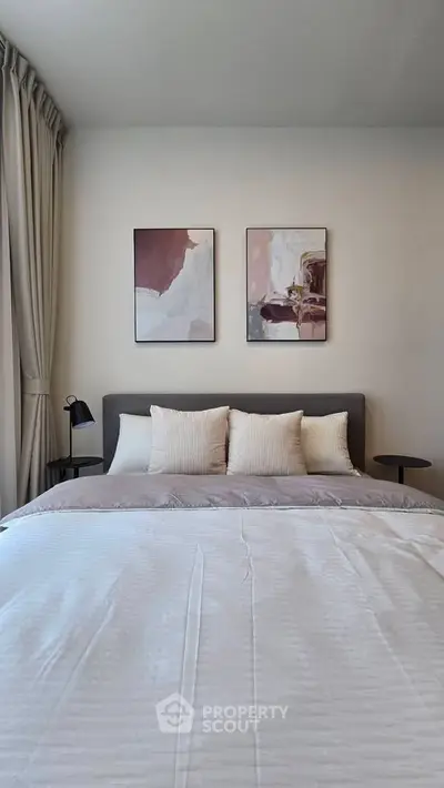 Elegant bedroom with modern decor and cozy bedding, featuring stylish artwork and soft lighting.