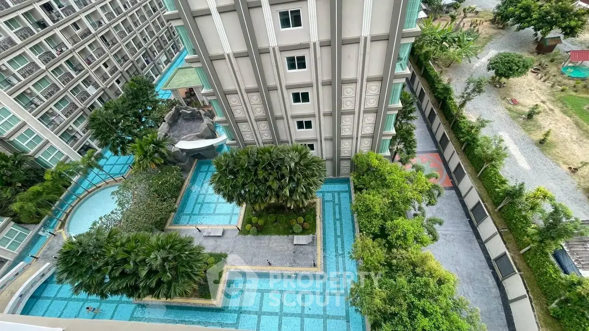 Stunning aerial view of modern residential building with lush greenery and pool area, perfect for urban living.