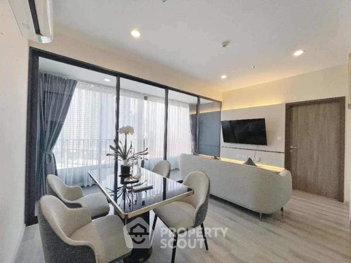 Modern living room with elegant dining area and large windows in a stylish apartment.
