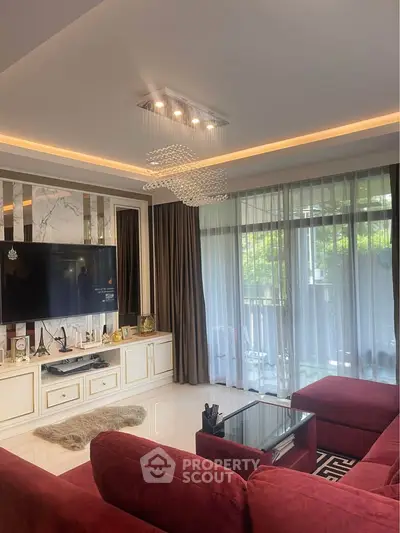 Luxurious living room with elegant decor, plush red sofas, and large windows offering natural light and garden views.